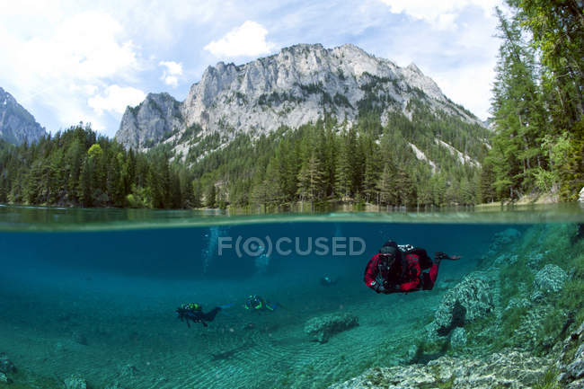 Austria, Styra, Tragoess, Green Lake, Diver swimming in lake with mountain landscape on background — Stock Photo
