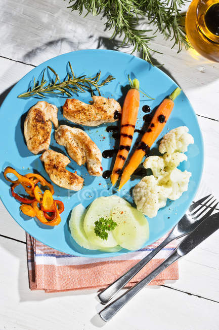 Elevated view of slices of chicken filet with cauliflower, carrots and bell pepper on plate — Stock Photo