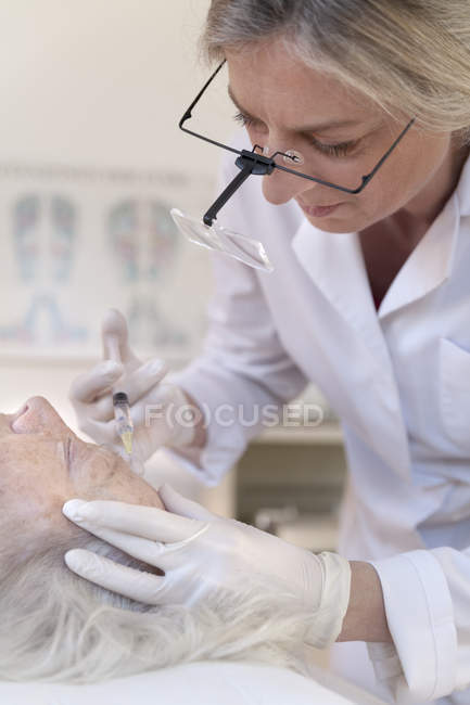Heilpraktikerin verabreicht Seniorin Injektionsakupunktur — Stockfoto