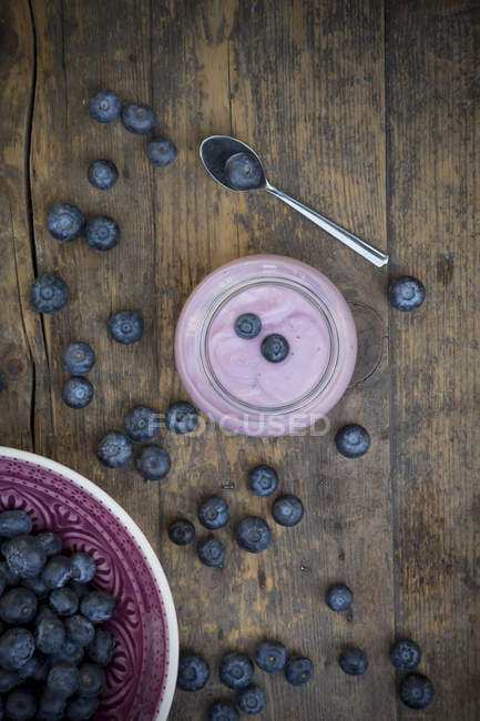 Mirtilli e bicchiere di yogurt ai mirtilli su legno scuro — Foto stock