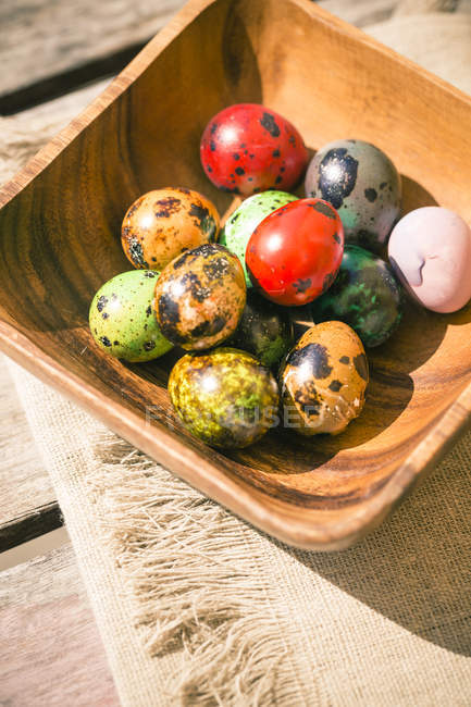 Підвищені подання дерев'яний кубок з барвисті великодні яйця на дерев'яну столову тканиною — стокове фото