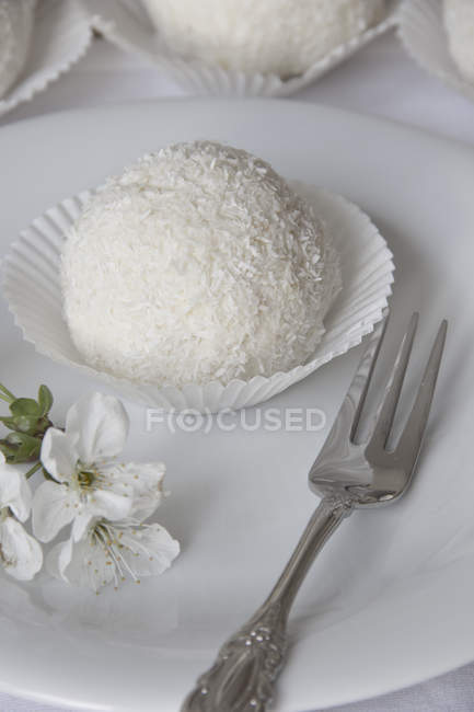 Closeup of snowball pastry on white plate with white flowers — Stock Photo
