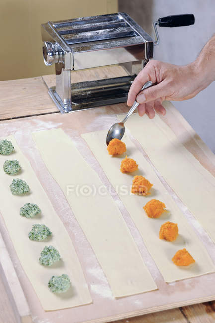 Spreading pumpkin filling on pasta dough for home-made tortelloni — Stock Photo