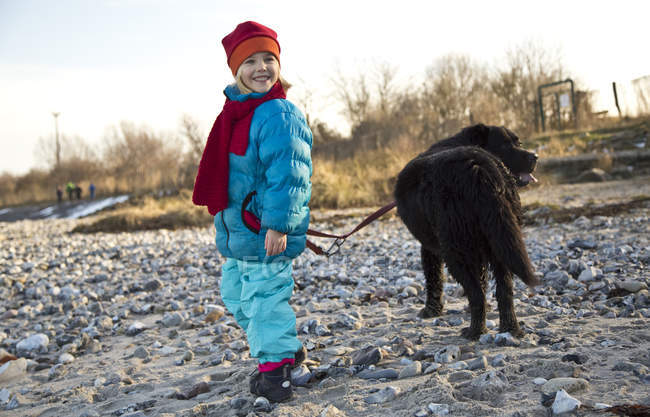 Petite fille marche avec labrador sur la plage — Photo de stock