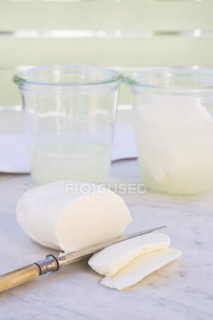 Mozzarella affettata, coltello e bicchieri su marmo bianco — Foto stock
