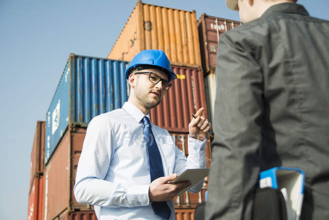 Geschäftsmann spricht Teenager am Containerterminal an — Stockfoto