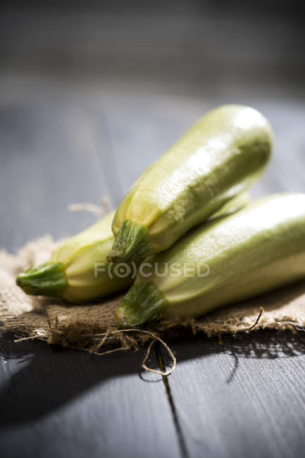 Zucchine bianche su superficie di legno con sacco — Foto stock