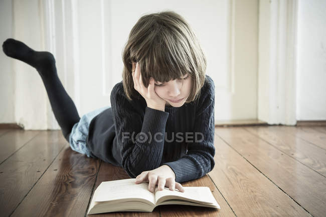 Retrato de la chica de lectura en el suelo de madera - foto de stock