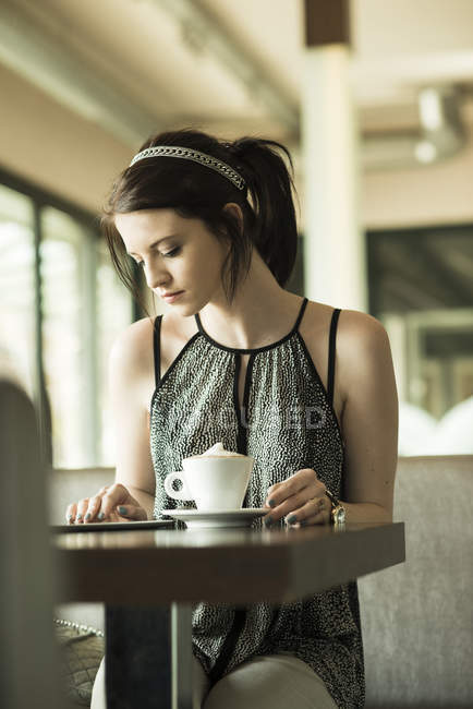 Портрет молодої жінки, за допомогою планшетного комп'ютера в кафе — стокове фото