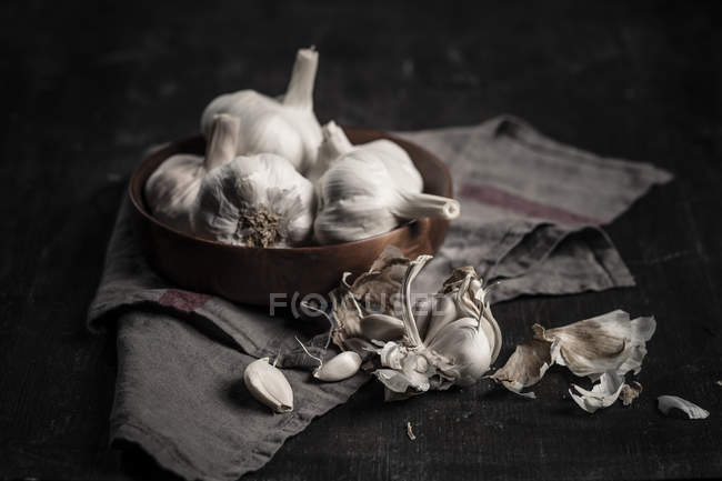 Dientes de ajo y bulbos sobre fondo oscuro con tela - foto de stock