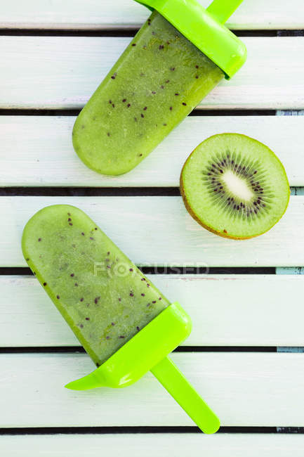 Two Kiwi Ice Cream Lollies And Half Of Kiwi On White Wood Refreshment Fruity Stock Photo Two Kiwi Ice Cream Lollies And Half Of Kiwi On White Wood Refreshment Fruity Stock Photo