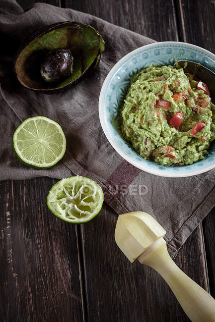 Чаша гуакамоле с выжатой лаймом и полым полом авокадо на кухонном полотенце — стоковое фото