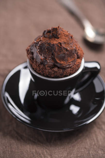 Black cup of chocolate cupcake on brown cloth — Stock Photo