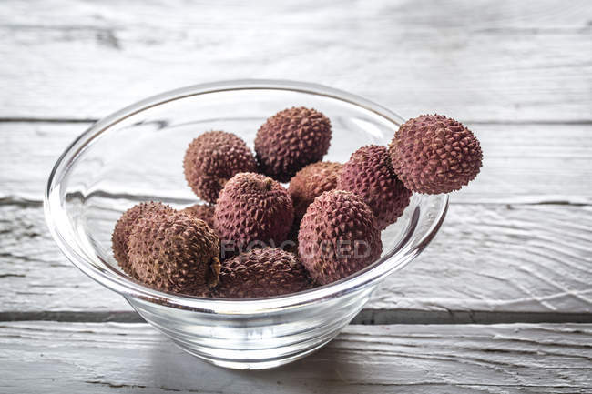 Glass bowl of lychees on wooden table — Stock Photo