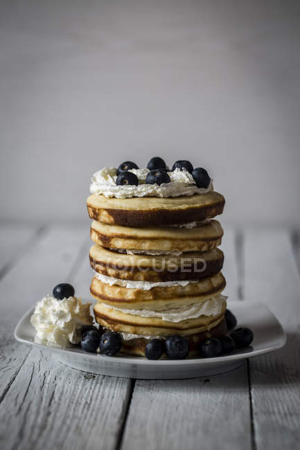 Stack of pancakes with blueberries on plate on wood — Stock Photo