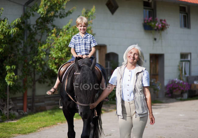 Donna matura leader ragazzo a cavallo — Foto stock