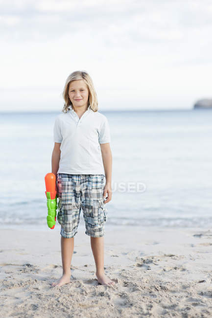 Junge mit Wasserpistole steht am Strand — Stockfoto