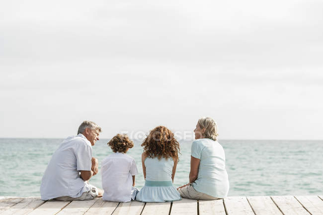 Nonni con nipoti seduti sul molo — Foto stock