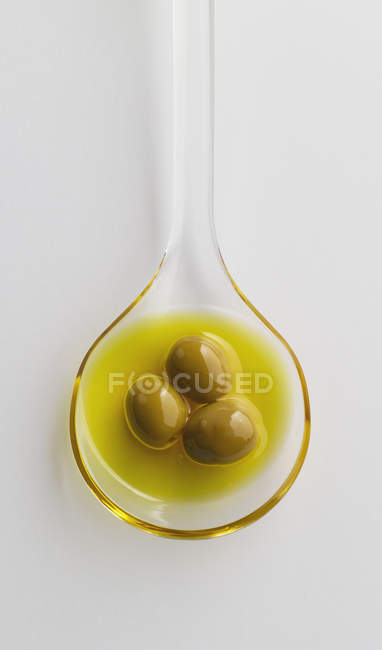 Oliare con olio in cucchiaio di plastica su fondo bianco, da vicino — Foto stock