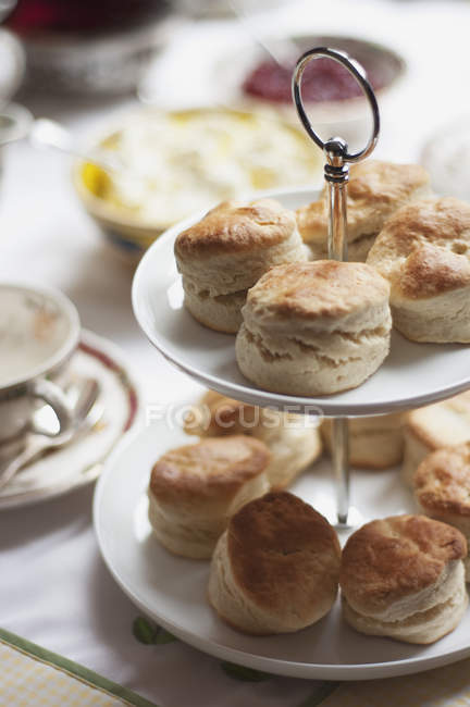 Appetizing baked scones on cakestand on table — Stock Photo