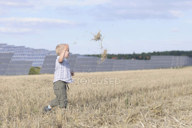 Хлопчик біжить у траві, сонячні панелі на задньому плані — стокове фото