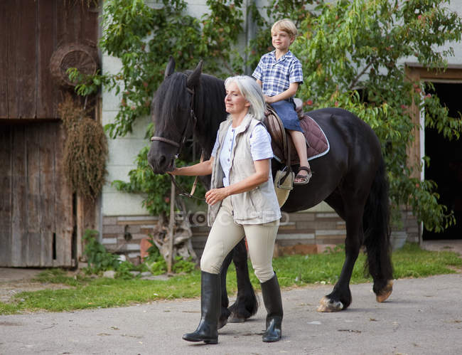 Madura mujer líder chico a caballo — Stock Photo