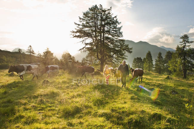 Jovem mulher caminhando com agricultor no prado alpino, Salzburgo, Áustria — Fotografia de Stock