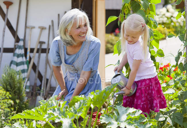 Mujer madura y chica en graden el cuidado de las plantas - foto de stock