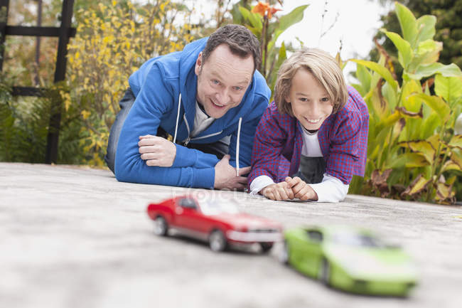 Padre e hijo jugando con juguetes de coche — Durante el día, exterior -  Stock Photo | #182498616