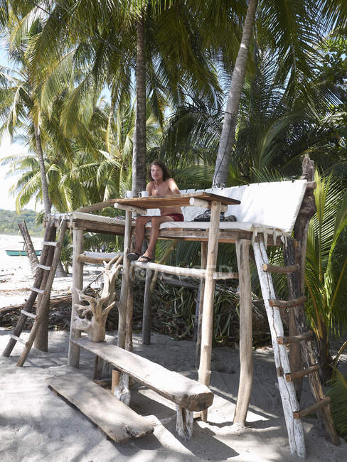 central-america-costa-rica-man-sitting-on-wooden-high-seat-under