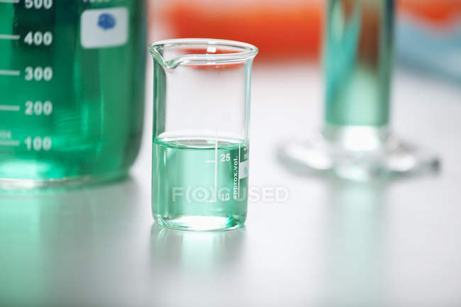 Measuring beaker with green liquid — Stock Photo