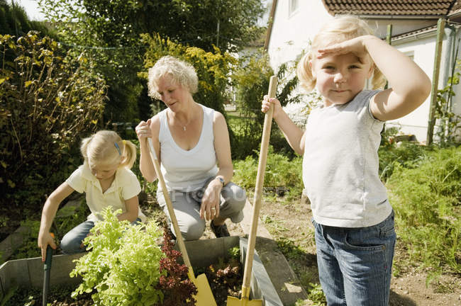 Grandmother with children working in garden — Stock Photo