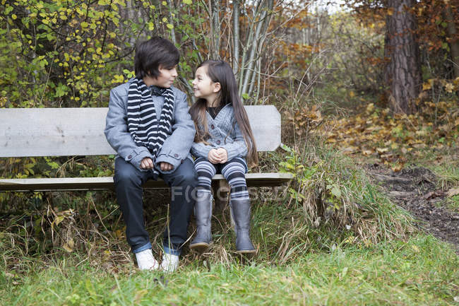 Niño y niña mirándose, sonriendo - foto de stock