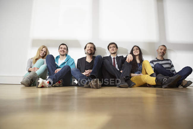 Hommes et femmes assis sur le sol dans un bureau moderne — Photo de stock