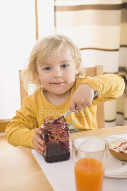 Sonriente chica comer mermelada para el desayuno - foto de stock