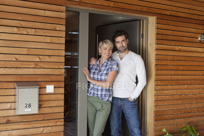 Mature couple standing at front door of house — Stock Photo