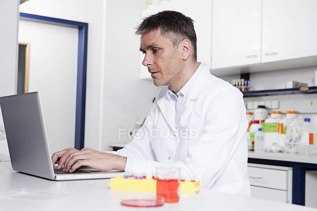 Scientifique utilisant un ordinateur portable en laboratoire — Photo de stock