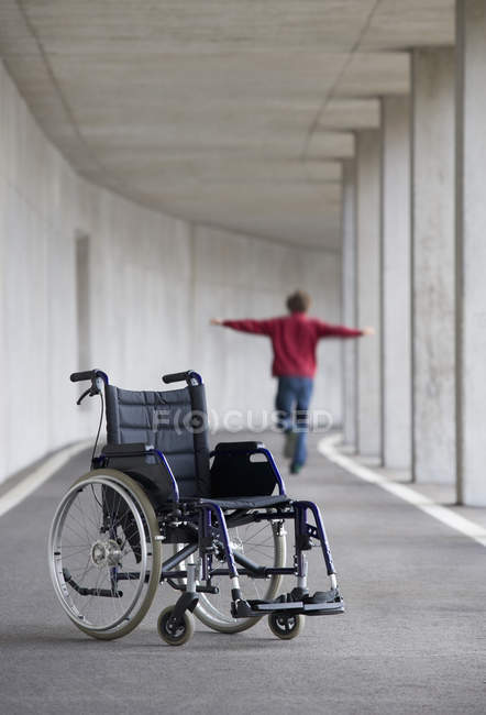 Jovem balanceamento com cadeira de rodas em primeiro plano — Fotografia de Stock
