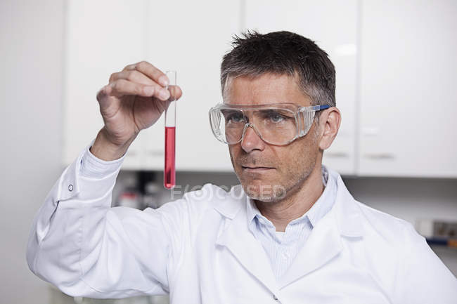 Ученый держит красную жидкость — стоковое фото