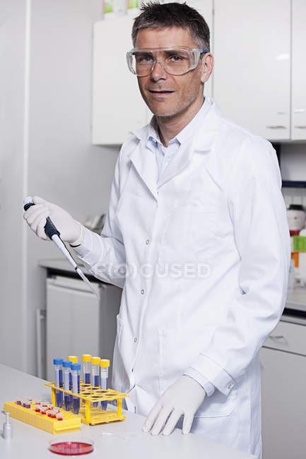 Scientist pouring red liquid with pipette — Stock Photo