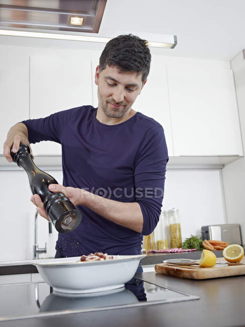 Hombre adulto medio cocinando alimentos en la cocina - foto de stock