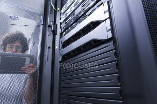 Female technician with tablet computer standing in server room — Stock Photo