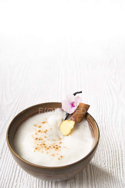 Chai Latte Té helado en un tazón de té con palo de canela y vaina de vainilla - foto de stock