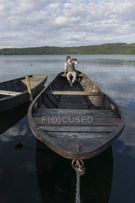 Германия, Рейнланд-Пфальц, озеро Лаах, человек, пьющий пиво и сидящий в лодке — стоковое фото