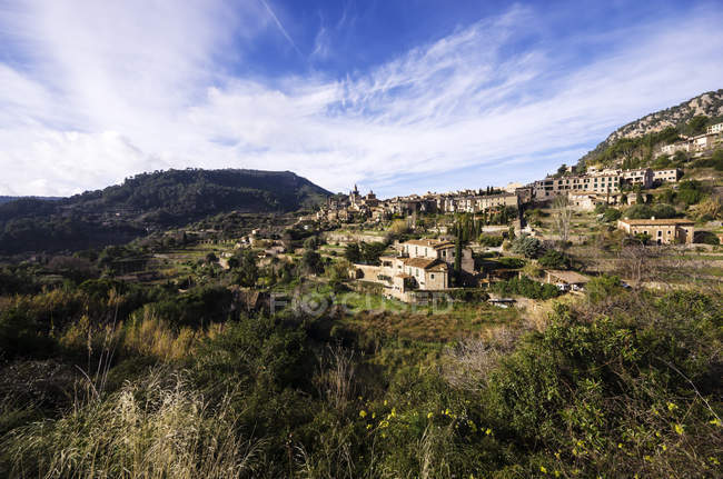 Espanha, Ilhas Baleares, Maiorca, Valldemossa, S 'Arxiduc e vista para a pequena cidade na colina verde sob nuvens — Fotografia de Stock