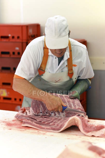 Man processing pig carcasses in a slaughterhouse — Stock Photo
