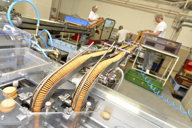 Arbeiter kontrollieren Kekse am Fließband in einer Backfabrik — Stockfoto