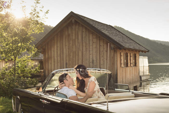 Couple assis dans une voiture vintage convertible devant une cabane en bois à Schliersee — Photo de stock