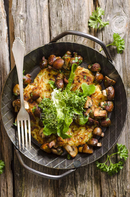 Fresh potato rosti in a pan with mushrooms and salad — Stock Photo