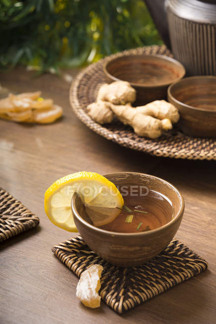 Thé au citron au gingembre dans un bol à thé, gingembre confit et frais — Photo de stock